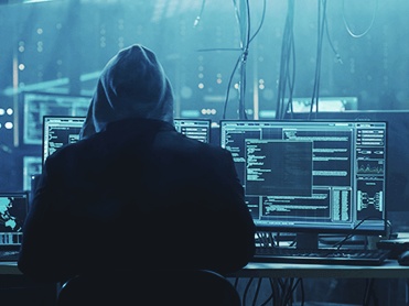 Cyberkrimineller sitzt vor einem Rechner mit geöffnetem Terminal-Fenster.