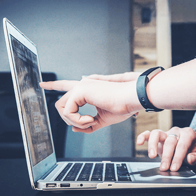 Hände die auf enen Laptop Bildschirm zeigen