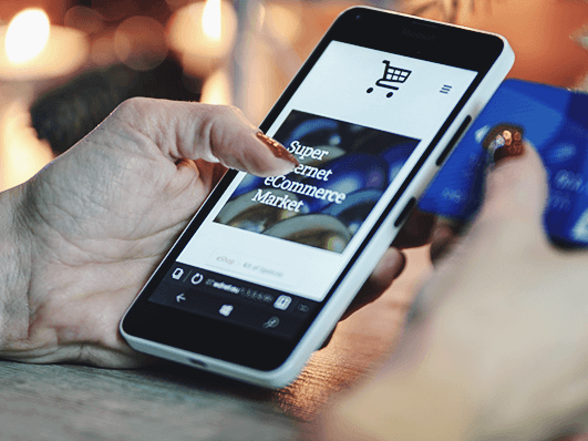 Person am Handy in einem Onlineshop und einer Kreditkarte in der Hand