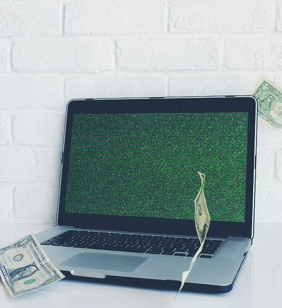 Laptop with code on screen and banknotes lying around