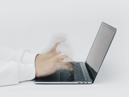 Hands typing on a laptop keyboard