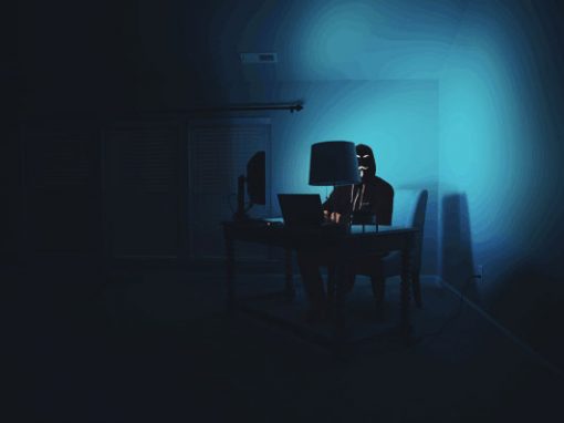 Cybercrimineller sitzt in einem dunklen Raum vor einem Computer