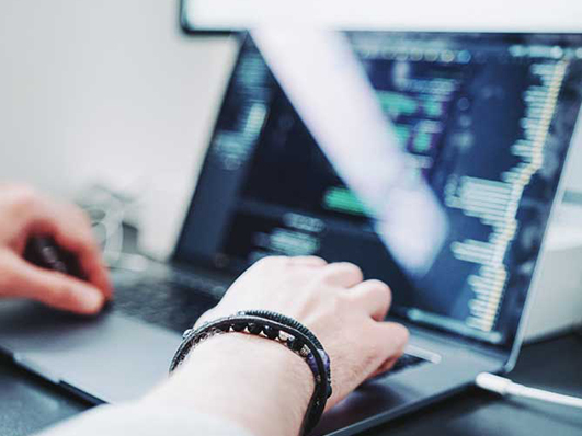 Person arbeitet am Laptop und schreibt Code
