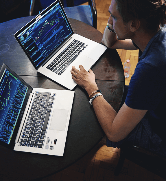 Person arbeitet mit zwei Laptops an Charts