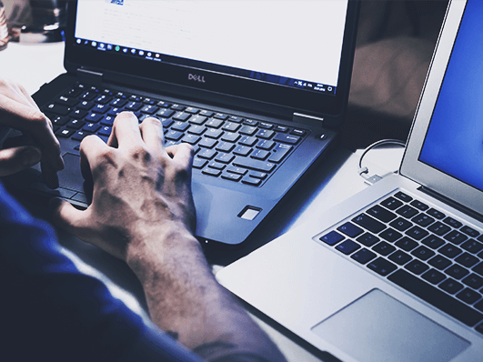 Person works on two laptops