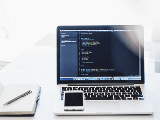 Cell phone, notebook and a laptop with code on the screen