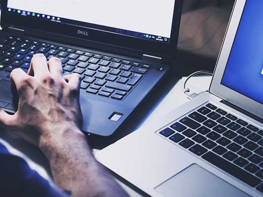 Person works on two laptops