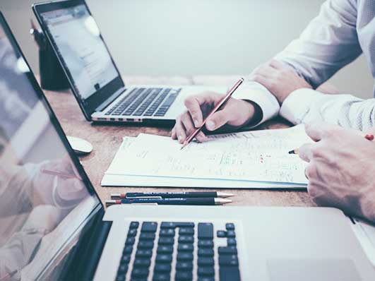 Two working people in front of laptops and notes