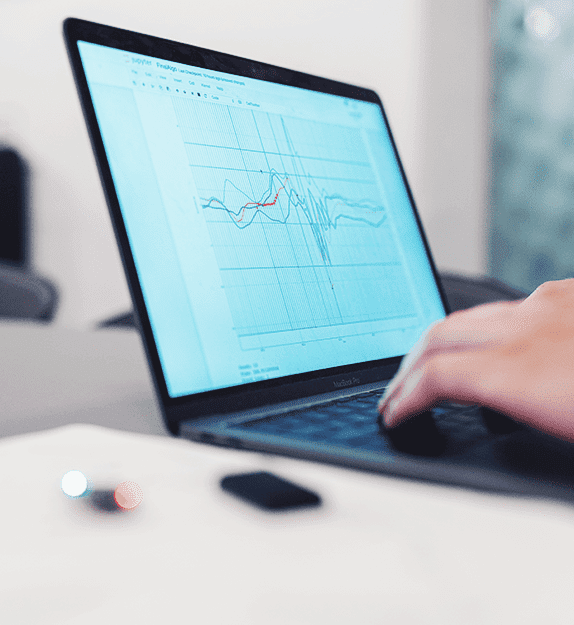 Hände die auf einer Laptop Tastatur schreiben und eine Statistik auf dem Bildschirm